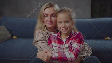 Portrait of joyful mom and daughter hugging indoor