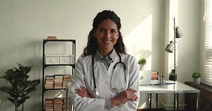 Confident female cardiologist in white coat pose indoors