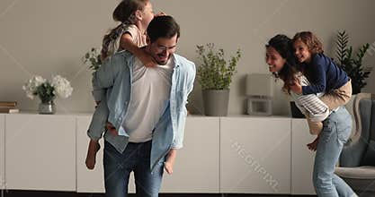 Happy energetic young couple parents playing with kids.