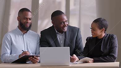 Portrait of three business partner young african man, mature elderly male leader and black ethnic woman sitting at table