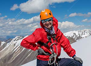 Portrait of smiling female alpinist in helmet in the high mountains