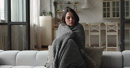 Woman wrapped in warm knitted plaid trembling with the cold