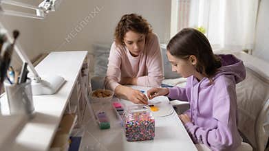 Smiling mother playing colorful boardgame with adolescent daughter.