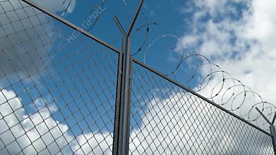 Barbed wire chain link fence against skyline timelapse at the restricted area