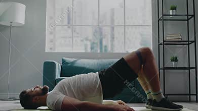 Muscular athlete practices bridge exercise with elastic belt