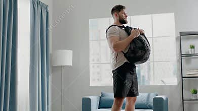 Concentrated guy practices squats with weight in backpack