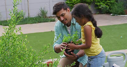 Hispanic father and daughter teaching planting flowers in the garden