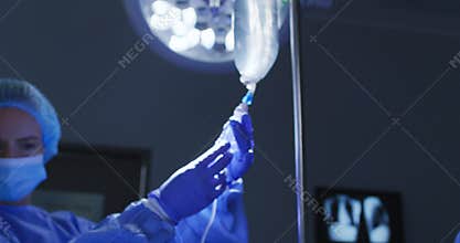 Doctors in protective clothing and face masks preparing patient for surgery in operating theatre