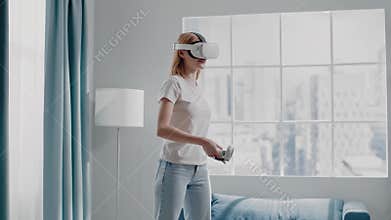 Woman in t-shirt plays videogame with VR headset in room