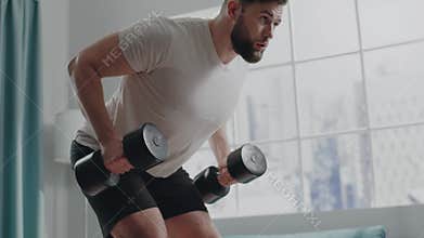 Bearded athlete man in t-shirt practices bent-over rows