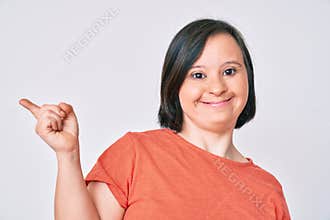 Brunette woman with down syndrome wearing casual clothes smiling happy pointing with hand and finger to the side
