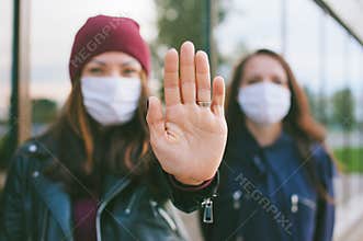 Hand on camera close-up, Female in medical masks. Against the backdrop of a glass building. Virus stop concept