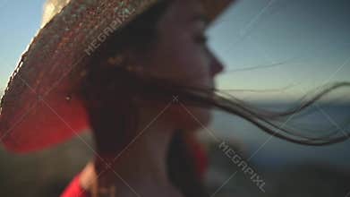 Close-up of a young Caucasian woman's hair fluttering in slow motion in the wind. Shallow depth of field. Girl in red