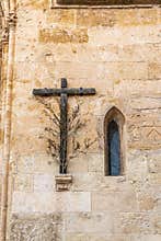 Wooden cross with olive branch next to a Gothic window. Church of Sineu
