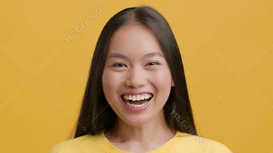 Portrait Of Joyful Chinese Woman Smiling To Camera, Yellow Background