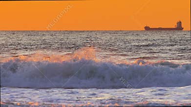 Golden sunrise over the sea. Ocean waves flood the shore