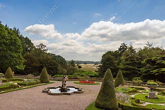Topiary, flower beds and small fountain in a formal garden in a park in Cheshire, UK.