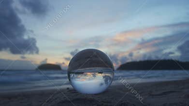 View of the island at sunset inside crystal ball on a pile of sand