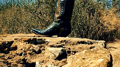 Female feet on the background of summer nature traditional American cowboy boots