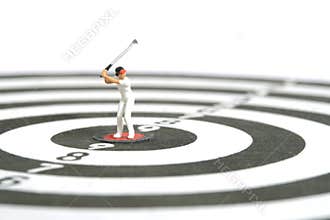 Miniature people toy figure photography. A girl golfer standing above dartboard at the center, isolated on white background