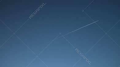 Jet airplane airliner flying leaving vapour trail across a blue cloudless sky