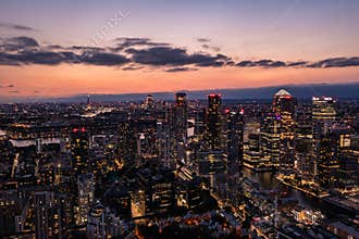 Panoramic aerial skyline view of east London at night with skyscrapers of Canary Wharf and beautiful colorful sky at