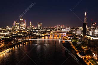 Night view of the beautiful London city with urban architectures and Tower Bridge at distance with skyscrapers and ocean