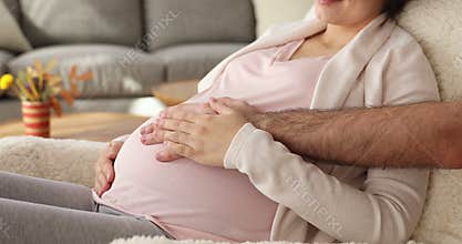 Happy young couple expecting childbirth, expressing affection to unborn baby.