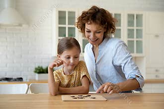 Smiling mother and little daughter playing wooden board game together