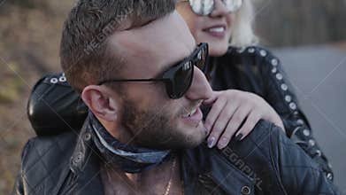 Portrait of happy biker's couple sitting in embraces on motorcycle and smiling