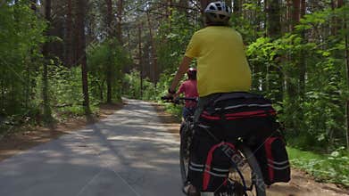 Two young men with backpacks ride bicycles along the road.