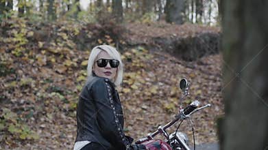 View of female biker sitting on motorcycle and turning to camera