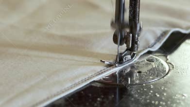 Sewing machine needle in motion as tailor stitches fabric in a workshop. Process of sewing fabric