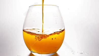 Graceful pouring of golden liquid into glass creates lively splash and bubbles, perfect for celebrations. Dynamic motion