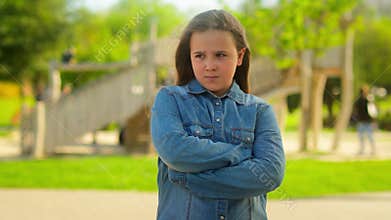 Portrait in park city outdoors offended angry alone sad serious Caucasian girl little child kid daughter orphan adopted
