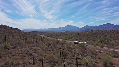 Tanker truck traversing a highway in a vast desert landscape with distant mountains