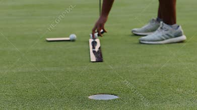 Golfer hits ball from podium with driver exercising on field. Close Up
