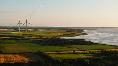 The setting sun casts long shadows across the North Sea in Denmark, highlighting the wind turbines standing tall in the