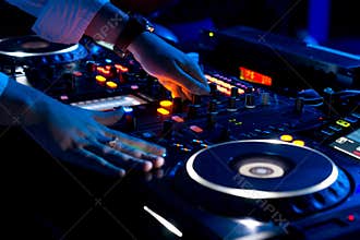 Hands of a DJ mixing music at a disco