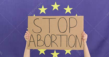 Woman activist holds cardboard sign with words Stop Abortion