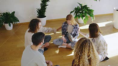 Young adults in an indoor group therapy session bond, talk, and support each other in a positive environment. They sit