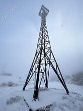 The iron tower is covered with snow. Two kilometers above sea level. A snow-capped mountain peak.