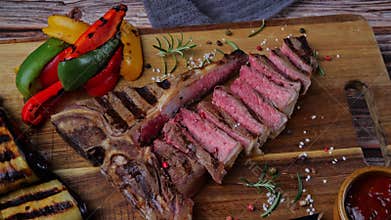 T- bone beef steak grilled sliced with grilled vegetables rotate wooden cutting board