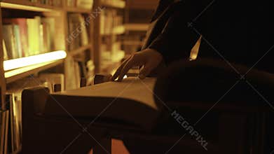 Close-up of mysterious man opening large book. Stock footage. Man opens book in dark library with flashing light. Secret
