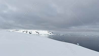 Large cruise ship and sailing boat in the bay near the Antarctic peninsula, a huge iceberg on mountains, the southern