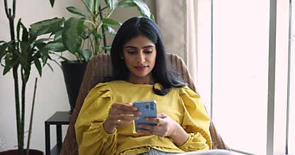 Carefree Indian woman using mobile phone at home