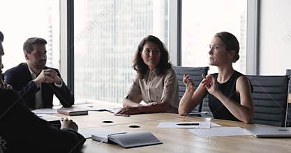 Serious young businesswoman talking to team of colleagues on meeting
