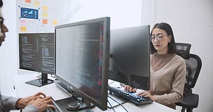Young adult Asian male, female software developer coding program on desktop computer. Man, woman work from home