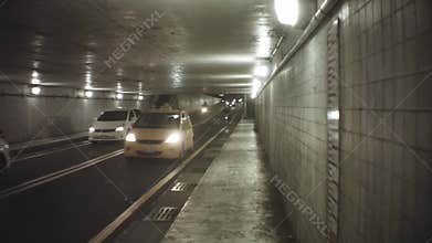 Still look down view of entrance of traffic tunnel with strong bring head light of vehicles cars and scooters motor bikes rushing