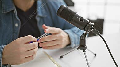 A bearded man podcasting in a studio with a professional microphone and notebook